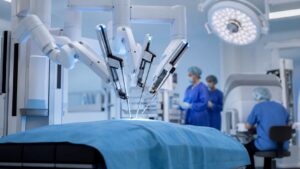 Surgical robotic arms positioned over a draped operating table in a bright sterile operating room